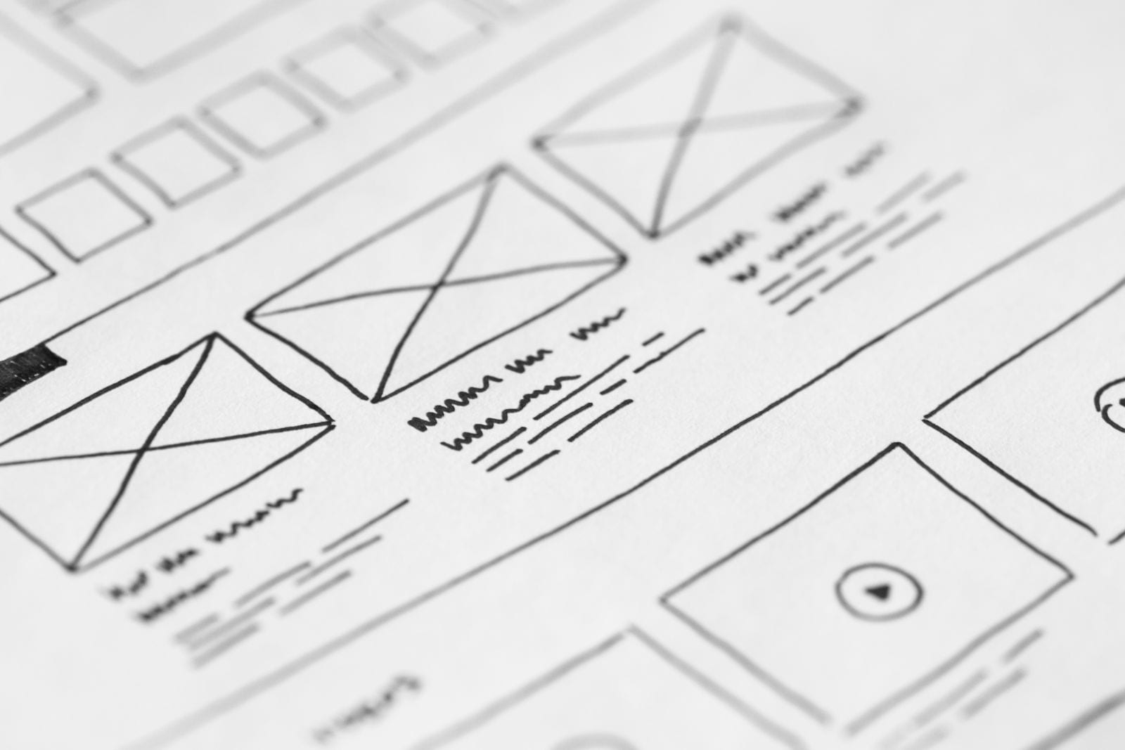 Hand-drawn wireframe on paper showing conventional website navigation structure and content grid